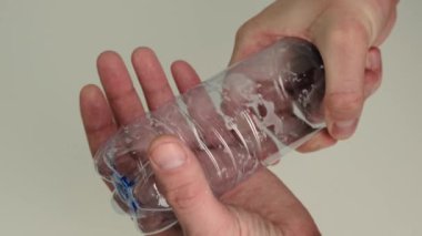 Boş bir plastik şişeyi elle ezmek. Kapat..
