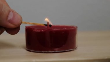 Yakın plan kadın elleri, karanlıkta, ağır çekimde ahşap kibritle bir mum yakar.