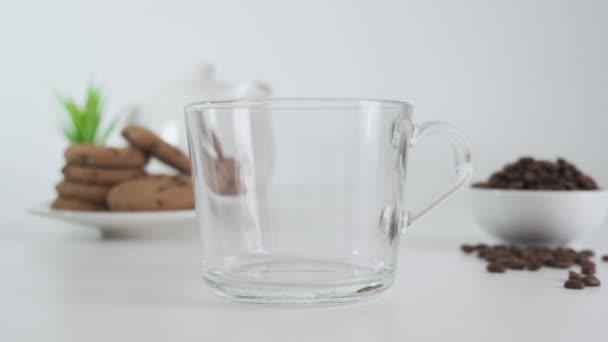 Glazen beker met granulaat van instant koffie over op witte achtergrond. Sluiten.. — Stockvideo