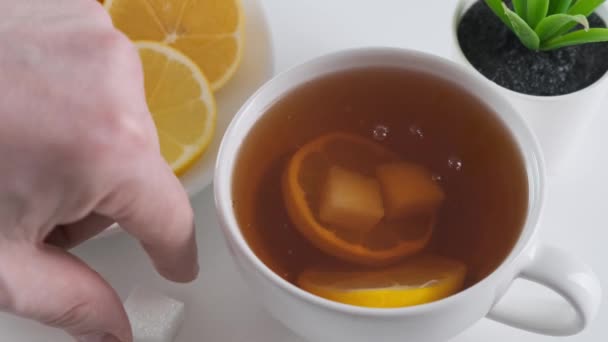Zucker in eine Tasse Tee auf dem Küchentisch geben. Nahaufnahme. — Stockvideo