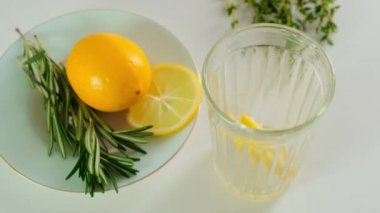 Preparing Cocktail with fresh cut lemon, rosemary in a glass. Close up.