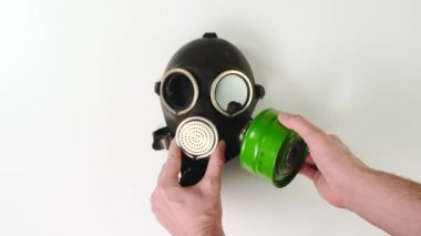 Erkek eller beyaz arka plandaki gaz maskesindeki yeşil filtreyi kontrol eder. Kapat..
