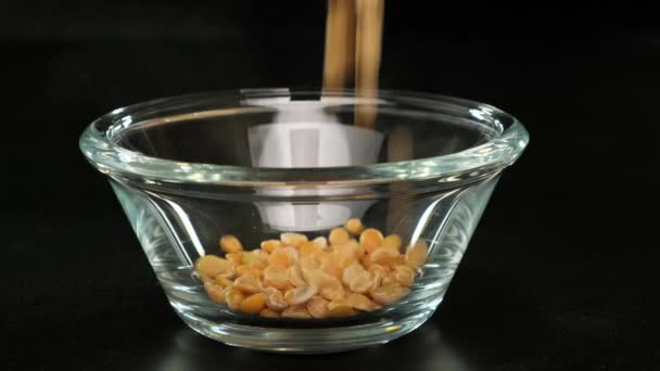 乾燥したエンドウ豆は黒の背景にガラスボウルに注がれます。閉じろ!. — ストック動画