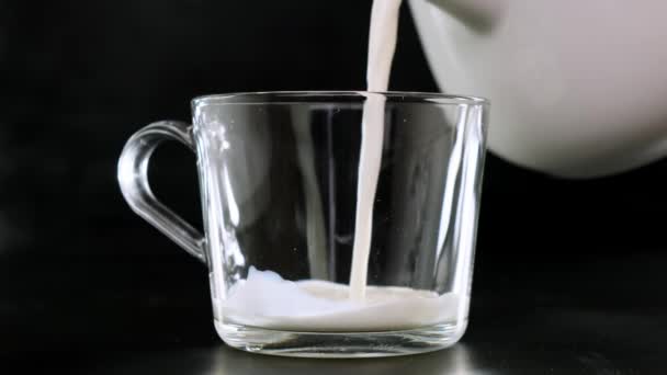 Koude melk wordt gegoten in een glazen zwarte achtergrond. Sluiten.. — Stockvideo