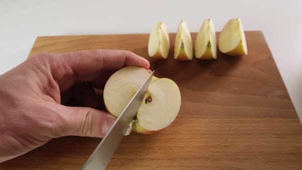 A pessoa corta uma maçã vermelha com faca em uma tábua de madeira. Fechar . — Vídeo de Stock