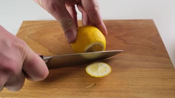 Top view close up of man cutting a lemon with knife on the wooden chopping board. Close up. — Stock Video