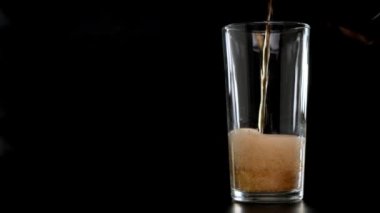 Cam siyah arkaplana lezzetli kola dökülüyor. Kapat..