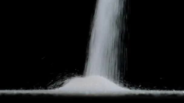 Pouring white sugar on black background. Close up. — Stock Video