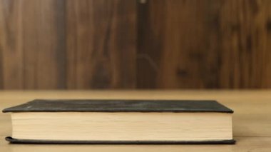 Kadın eli, kitapları ahşap arka plandaki masaya koyar. Kapat..