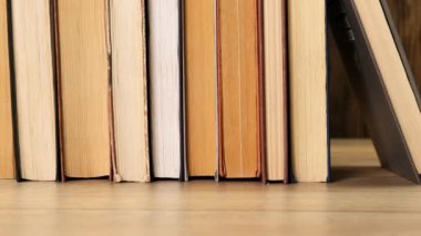 Person taking a book off a bookshelf in a library or book shop. Close up.