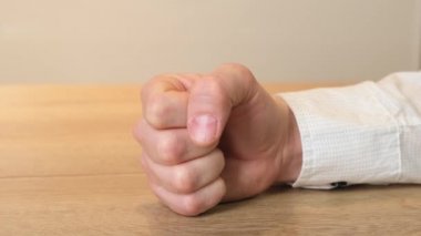 Close up Fist of angry man beats on the table. Close up.