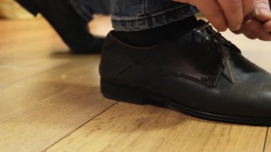 Man tying patent black leather shoes. Close up.