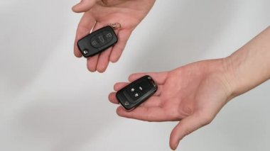 A man offers two car keys. Another picks and takes one. Close up.