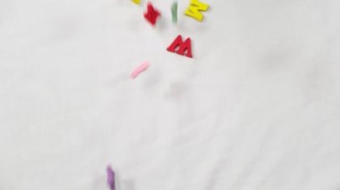 Color letters fall down on the white background. Close up,