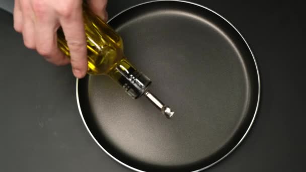 Man pouring cooking oil on the black pan Top view. Close up. — Stok video