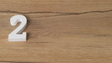 Male hand puts numbers 2020 year, white figures on wooden background, Close up.