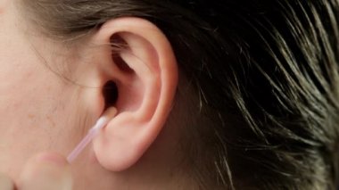 Close up of man using stick of cotton swab for ears cleaning. Close up.