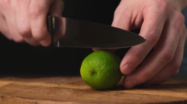 Sliced in half fresh lime with knife on wooden chopping board. Close up.