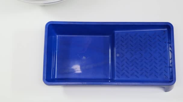 Person pours gray paint into a blue tray for painting walls. Close up. — Stok video