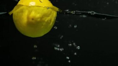 Lemon falls in the water in slow motion.on black background. Close up.