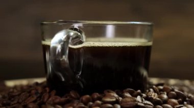 Glass cup of coffee with beans Rotating Rotating on black background. Close up.