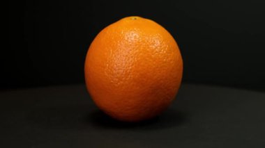 Orange fruit rotating on a black background. Close up
