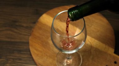Skilled sommelier pouring red wine from bottle into Glass. Close up.