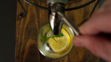 Buzlu sağlıklı taze limonata ve büyük testiden cama nane şekeri döküyorum. Kapatın. Üst görünüm.