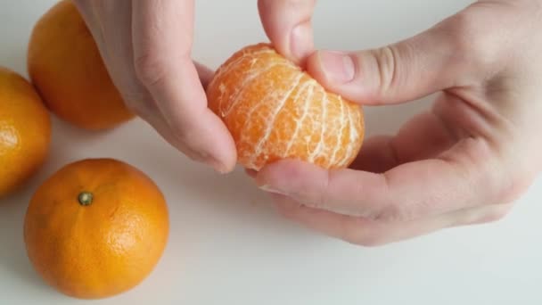 Χέρι Ξεφλουδίζει Ένα Μανταρίνι Πορτοκάλι Λευκό Φόντο Κλείσε — Αρχείο Βίντεο