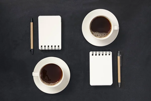 Tasse de café avec cahier et stylo noir sur fond noir. Planificateur d'entreprise. — Photo