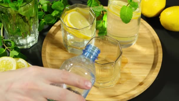 Ruka nalévá do sklenice limonádu. Koktejly citrusové vody s citronem. — Stock video