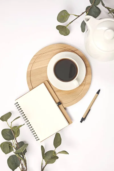Šálek kávy, tužka, větev s listem, papírová poznámka na bílém pozadí. — Stock fotografie