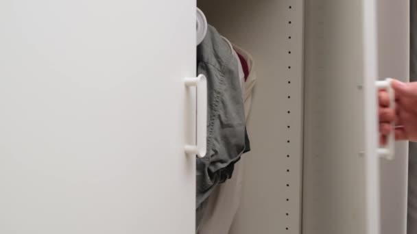 Мужчина откройте дверь шкафа и выберите одну чистую белую рубашку. Закрыть . — стоковое видео