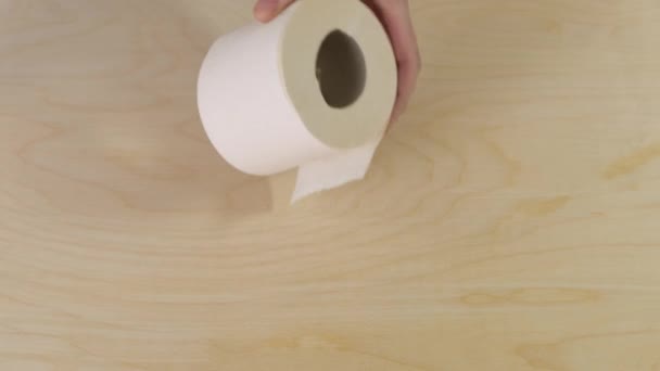 Руки держат рулон туалетной бумаги на деревянном фоне. Закрыть . — стоковое видео