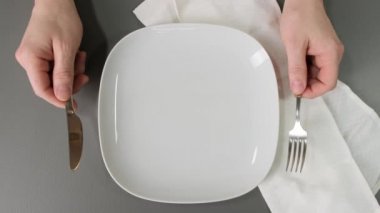 Elleri çatal bıçaklı, boş tabak ve peçeteli..