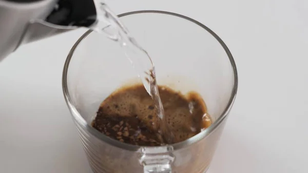 Haciendo café negro instantáneo en taza de vidrio. Vierte agua caliente. Movimiento lento . — Foto de Stock
