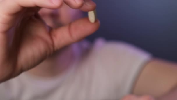 Muž si bere bílou pilulku a jí. Zavřít. — Stock video