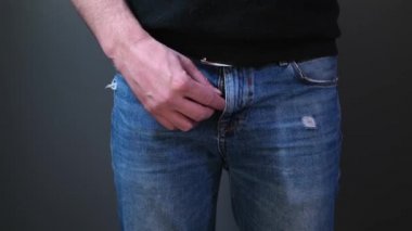 Siyahlı adam kot pantolonunu bağlıyor. Kapat..