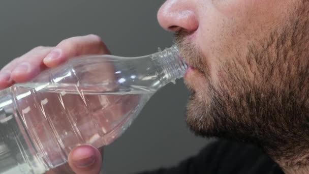 Man drinkt water uit een plastic fles close up. — Stockvideo