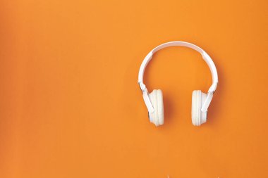 Kulaklıklar turuncu arka planda. Müzik konsepti. Üst görünüm.