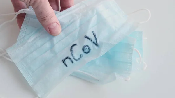 Hand auf den Tisch legen Maske Medical Protection mit den Buchstaben nCoV. Nahaufnahme. — Stockfoto
