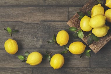 Ağaç yapraklı ahşap bir tabak taze limon..