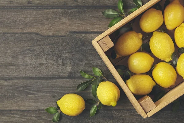 Wooden box of fresh lemons with tree leaves. — Stock Photo, Image