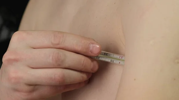 Man measures the temperature with a thermometer. Close up. — Stock Photo, Image