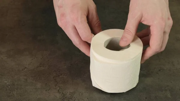 Hände reißen ein Stück Toilettenpapier von einer Rolle. Nahaufnahme. — Stockfoto