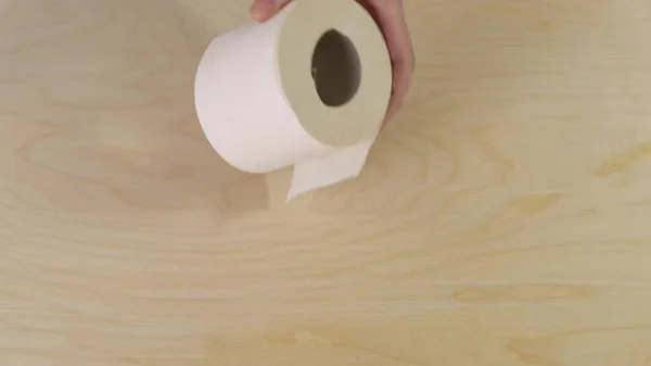 Hände halten Toilettenpapier auf hölzernem Hintergrund. Nahaufnahme. — Stockfoto