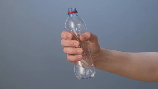 Hand zerquetscht eine Plastikflasche. Nahaufnahme. — Stockfoto