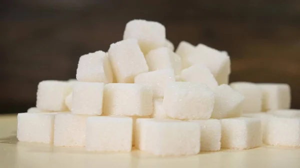 A pile of sugar pieces rotates on black background. Close up. — Stock Photo, Image