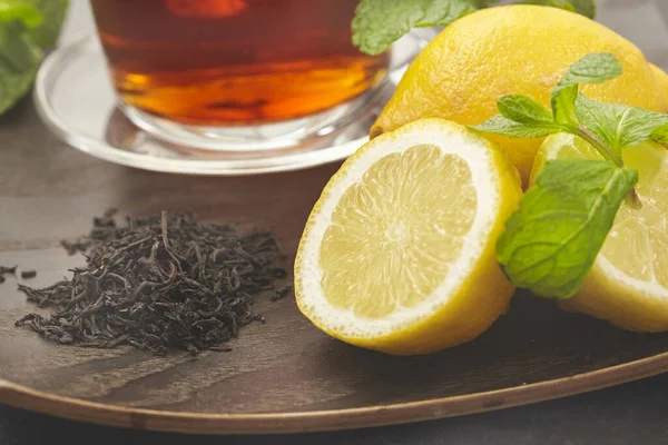 Taza con té, limón y hoja verde sobre fondo de madera . —  Fotos de Stock