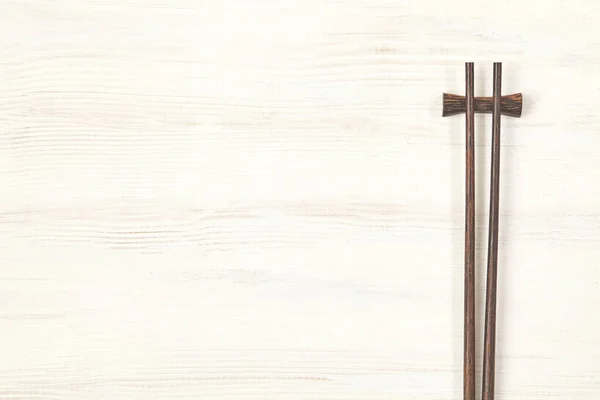Dark wood chopsticks on white board. Copy space. — Stock Photo, Image